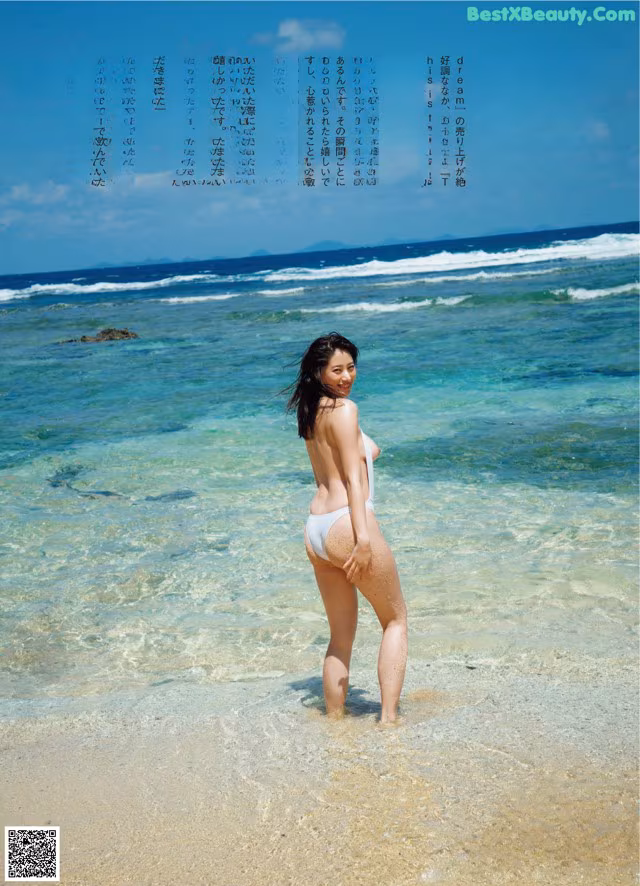 A woman in a white bikini standing in the ocean.