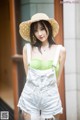 A woman wearing a straw hat and overalls posing for a picture.