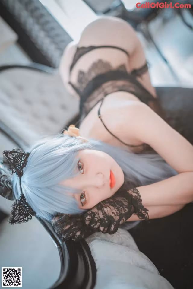 A woman with blue hair laying on a couch.
