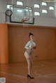 A woman standing on a basketball court next to a basketball hoop.