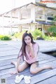 A woman sitting on a wooden dock next to a house.