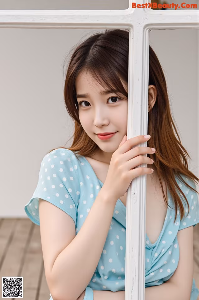 A young woman leaning against a white fence.