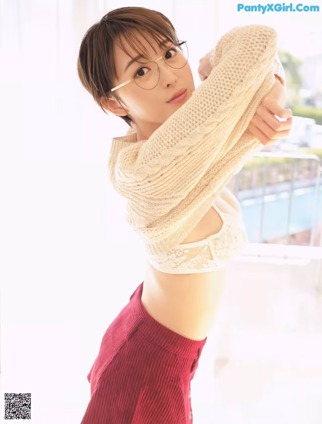 A woman wearing glasses and a sweater posing for a picture.