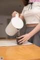 A woman pouring water into a cup on a table.