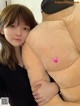 A woman holding a giant teddy bear with a pink heart on it.