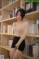 A woman standing in front of a bookshelf full of books.