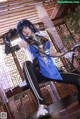 A woman in a blue and black outfit sitting on a table.