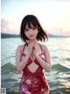 A woman in a red bathing suit standing in the water.