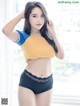 A woman in a yellow and blue shirt and black panties.