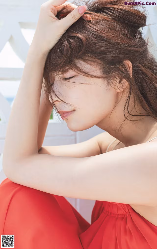 A woman in a red dress sitting on a white bench.