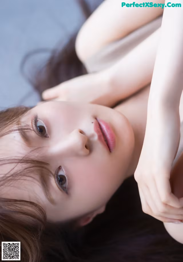 A woman laying on top of a bed next to a pillow.