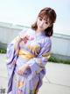 A woman in a purple kimono posing for a picture.