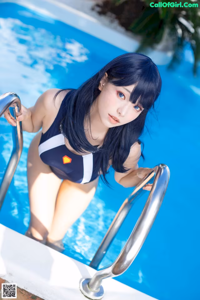 A woman in a bathing suit standing next to a swimming pool.