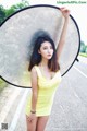 A woman in a yellow dress holding a large umbrella.